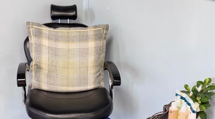 Comfortable salon chair with plaid pillow at K G Beauty, Edinburgh, Scotland, GB, offering a relaxing atmosphere.