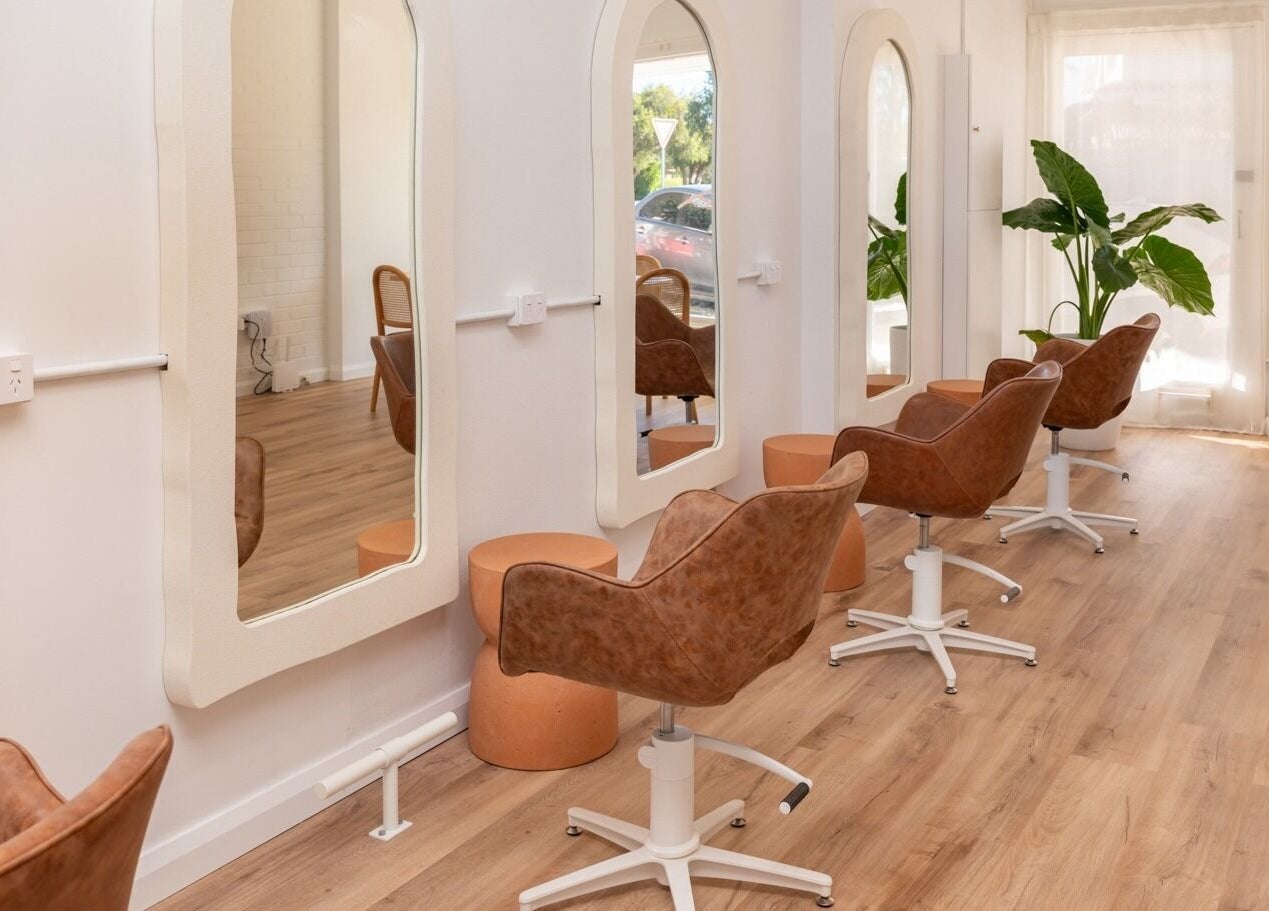 Bright salon interior at The Aura Colab, Loftus, New South Wales, AU featuring stylish chairs and large mirrors.