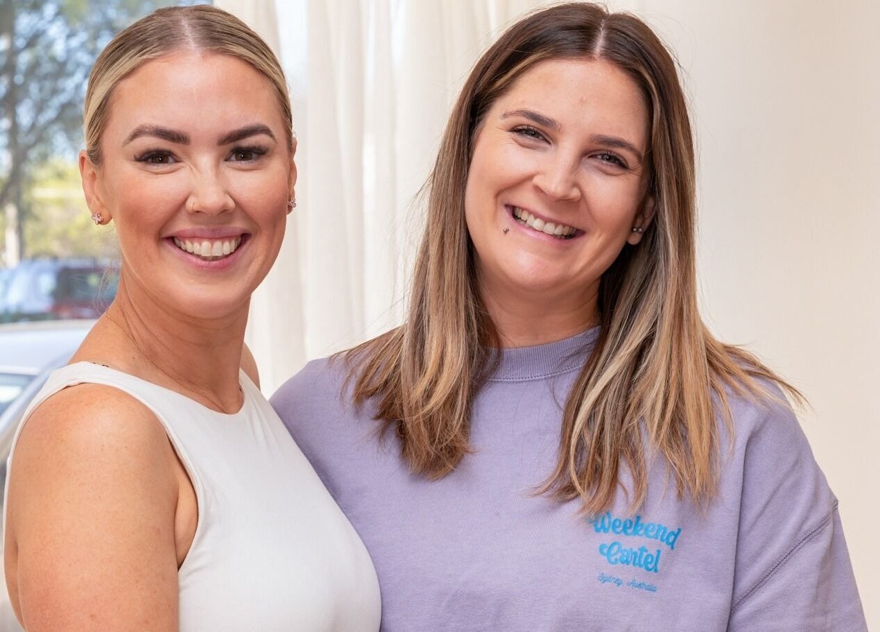 Two smiling women at The Aura Colab, Loftus, New South Wales, AU, enjoying a warm ambiance.