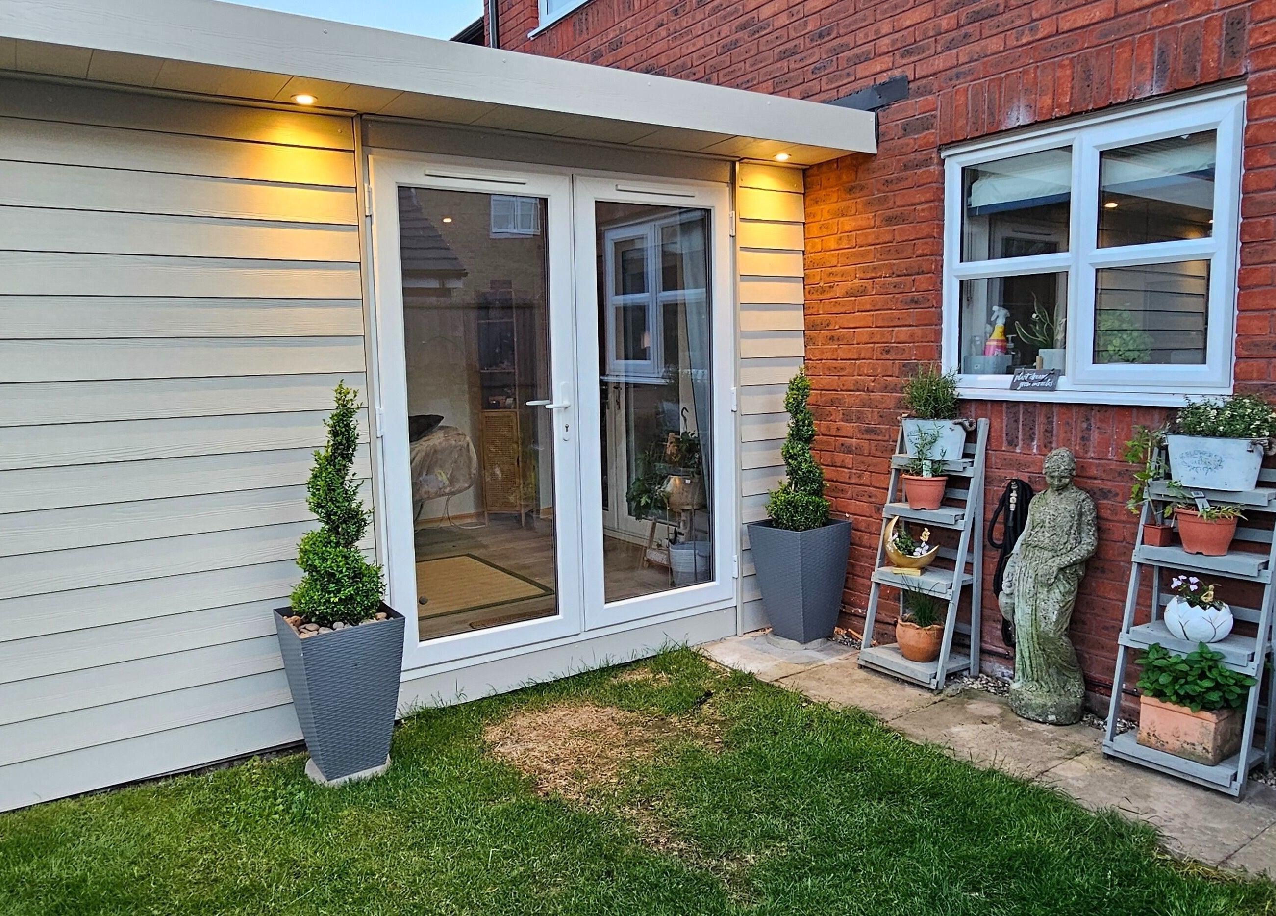 Outdoor garden view of Calm by Nature Reflexology in Bromborough, England, GB with potted plants and seating.