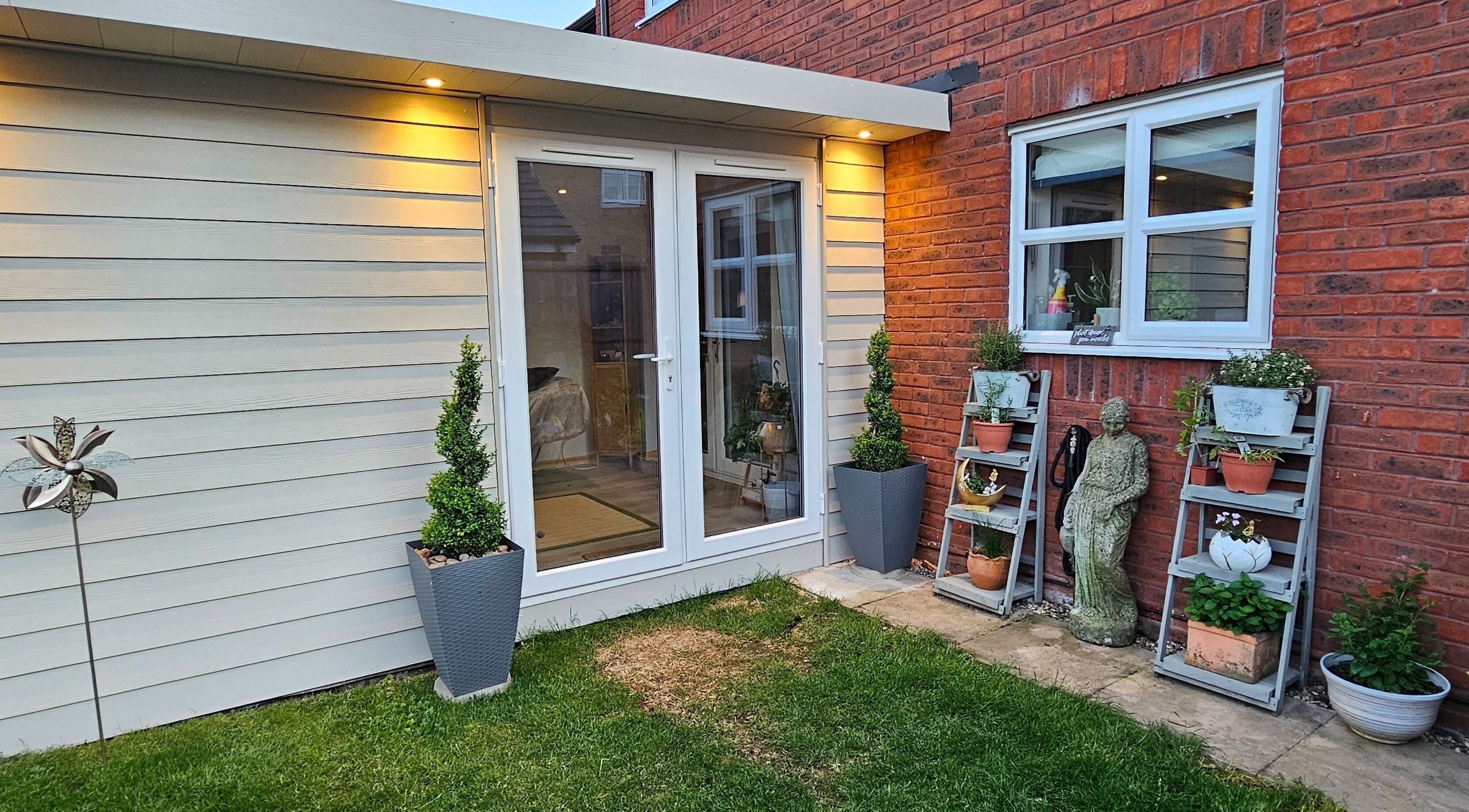Outdoor garden view of Calm by Nature Reflexology in Bromborough, England, GB with potted plants and seating.