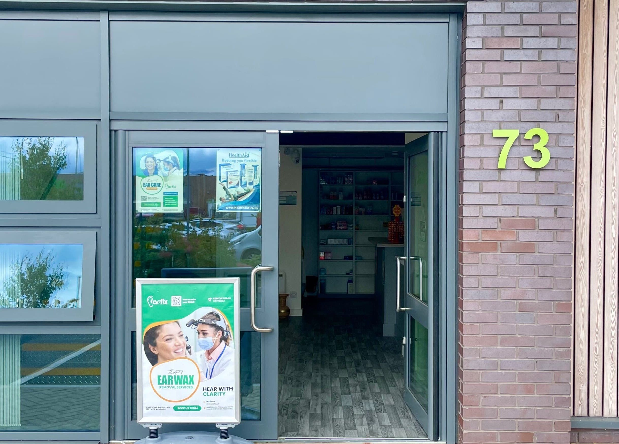 Entrance of Jrapha Earfix & Travel Clinic in Wellingborough, England, GB, showcasing clean glass doors.