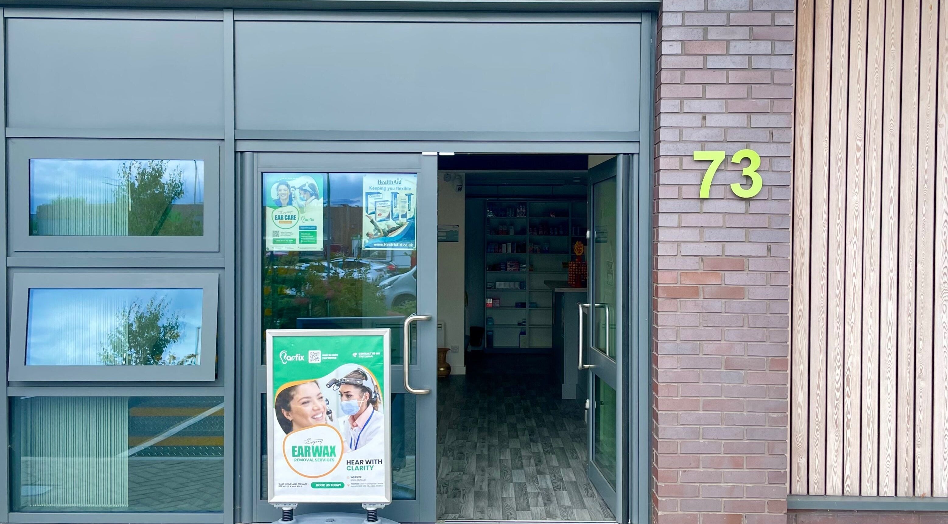 Entrance of Jrapha Earfix & Travel Clinic in Wellingborough, England, GB, showcasing clean glass doors.