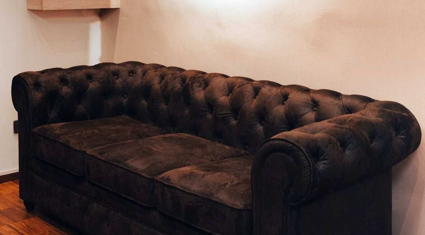 Divano in pelle scura presso Clippers Barbershop, Trescore Balneario, Lombardia, IT.