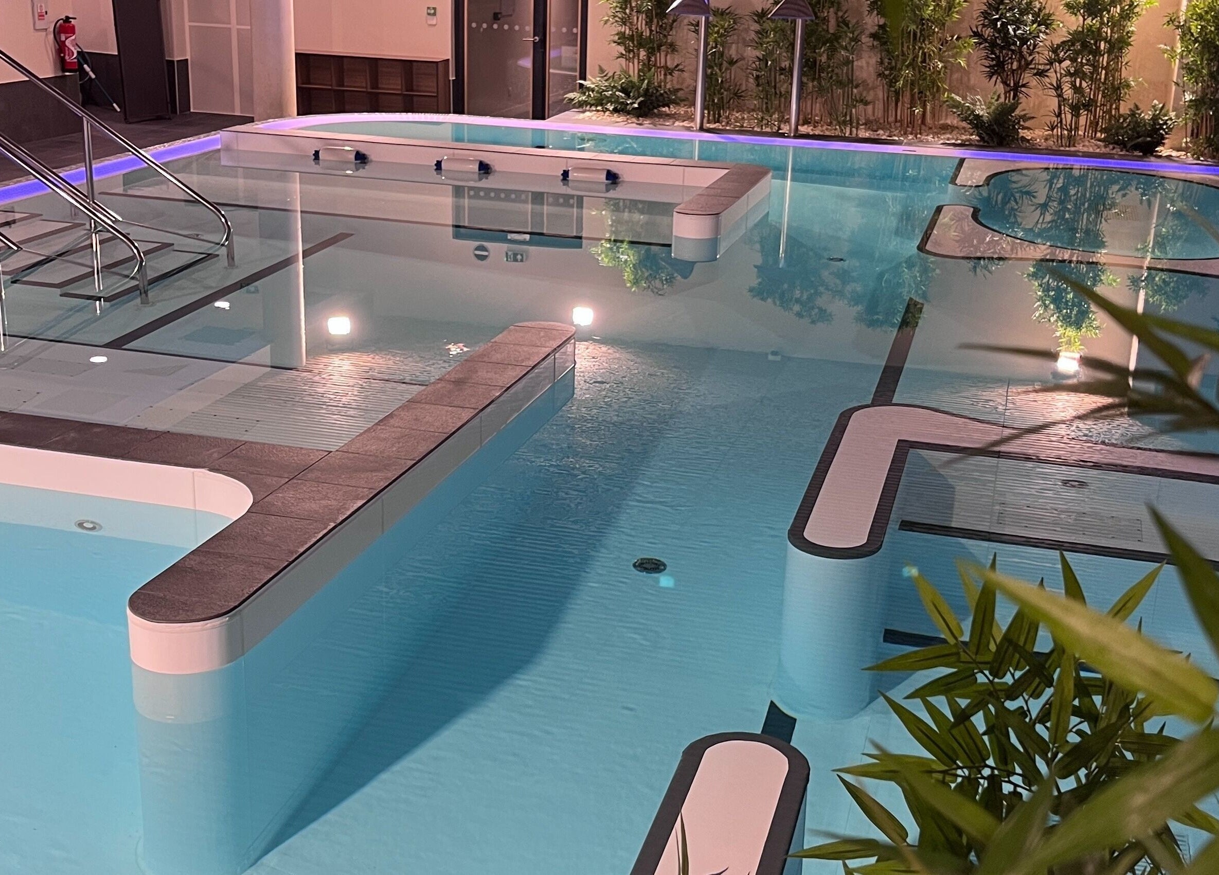 Luxurious pool at Spa Arzana, Rueil-Malmaison, Île-de-France, FR, surrounded by ambient lights and greenery.