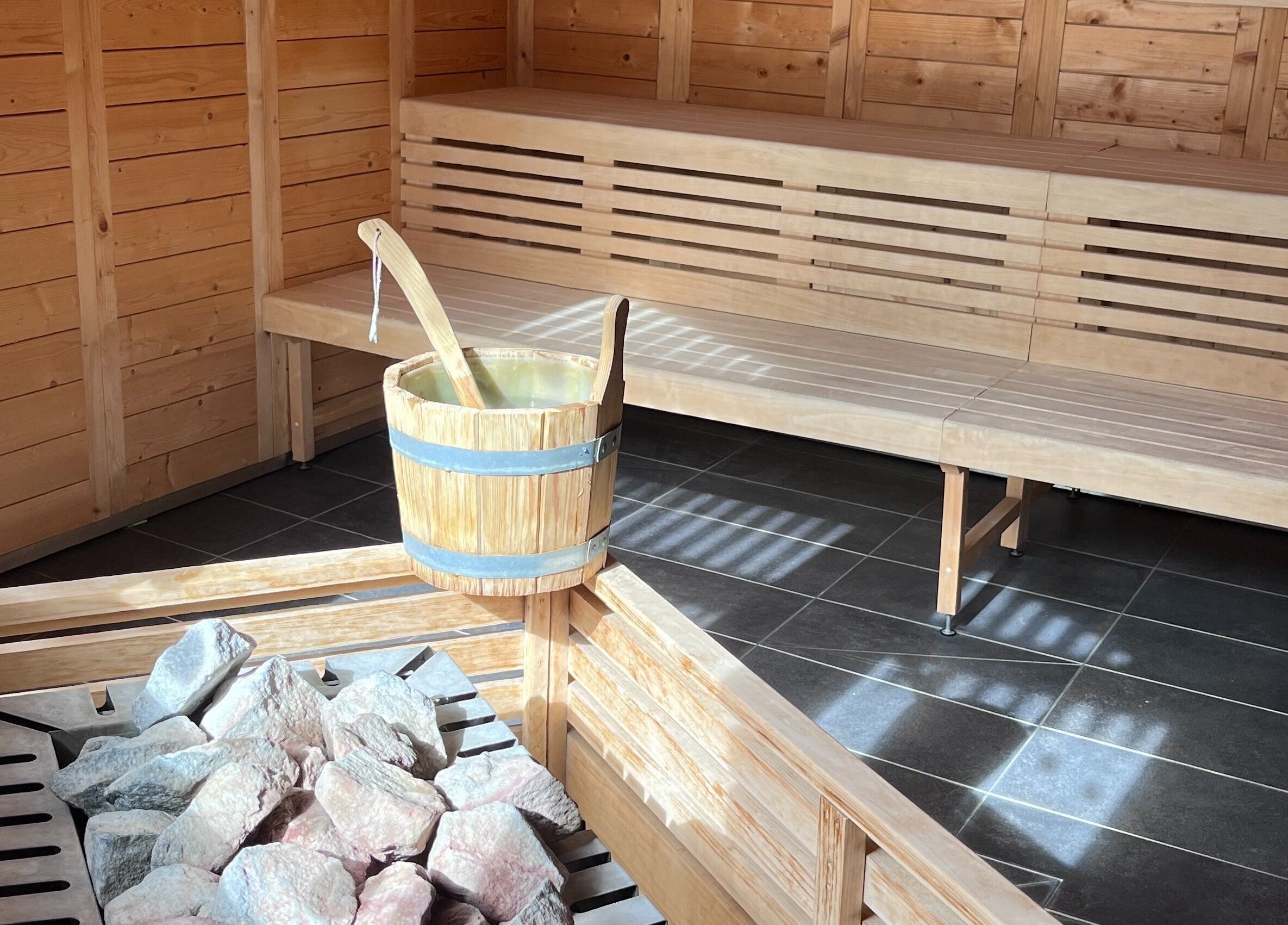 Rustic sauna room at Spa Arzana, Rueil-Malmaison, Île-de-France, FR, featuring wooden benches and heater.