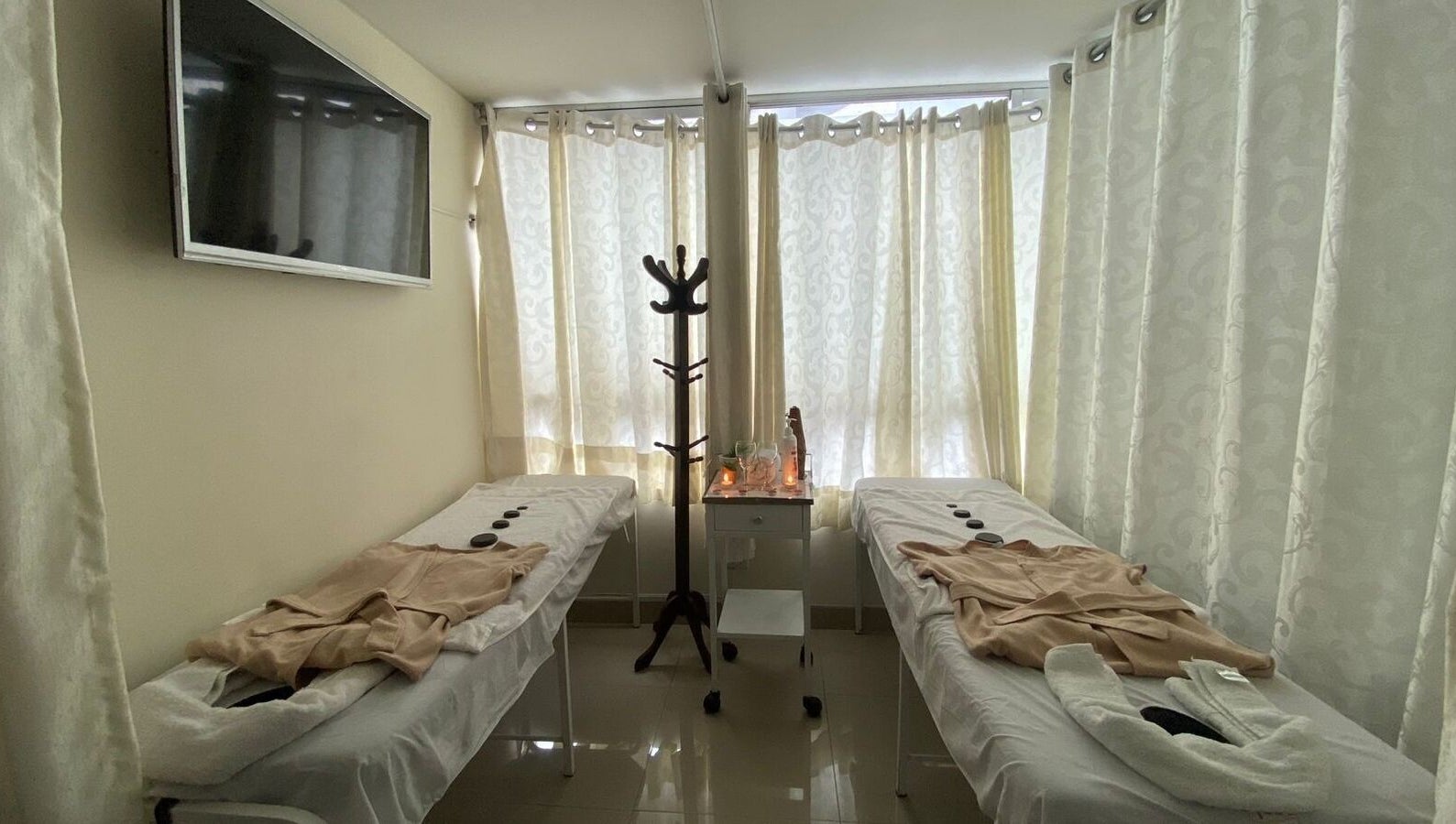 Sala de tratamiento doble en Spa Musas, Miraflores, Provincia De Lima, PE, con mesas de masaje y cortinas claras.