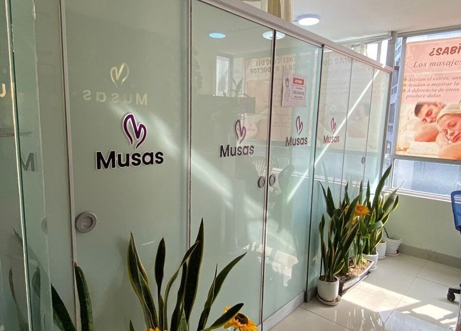 Entrada de Spa Musas en Miraflores, Provincia De Lima, PE, con cabinas de cristal y plantas decorativas.