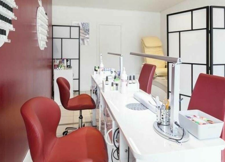 Intérieur élégant de Phuong Esthetic and Nails Overijse, Overijse, Vlaanderen, BE avec chaises rouges et stations de nail art.