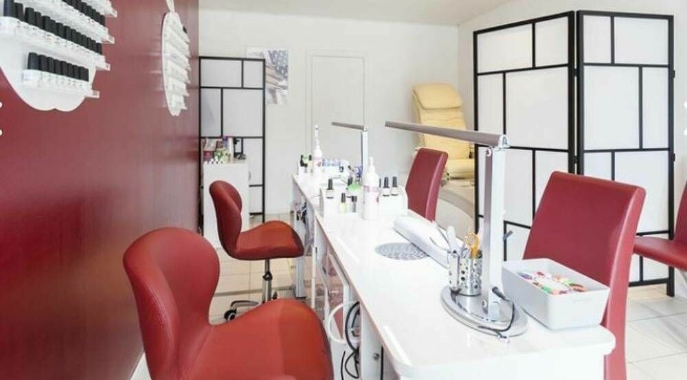 Intérieur élégant de Phuong Esthetic and Nails Overijse, Overijse, Vlaanderen, BE avec chaises rouges et stations de nail art.