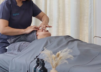 Therapist massaging a client's face at Spaholics Home Wellness, Dubai, Dubai, AE.