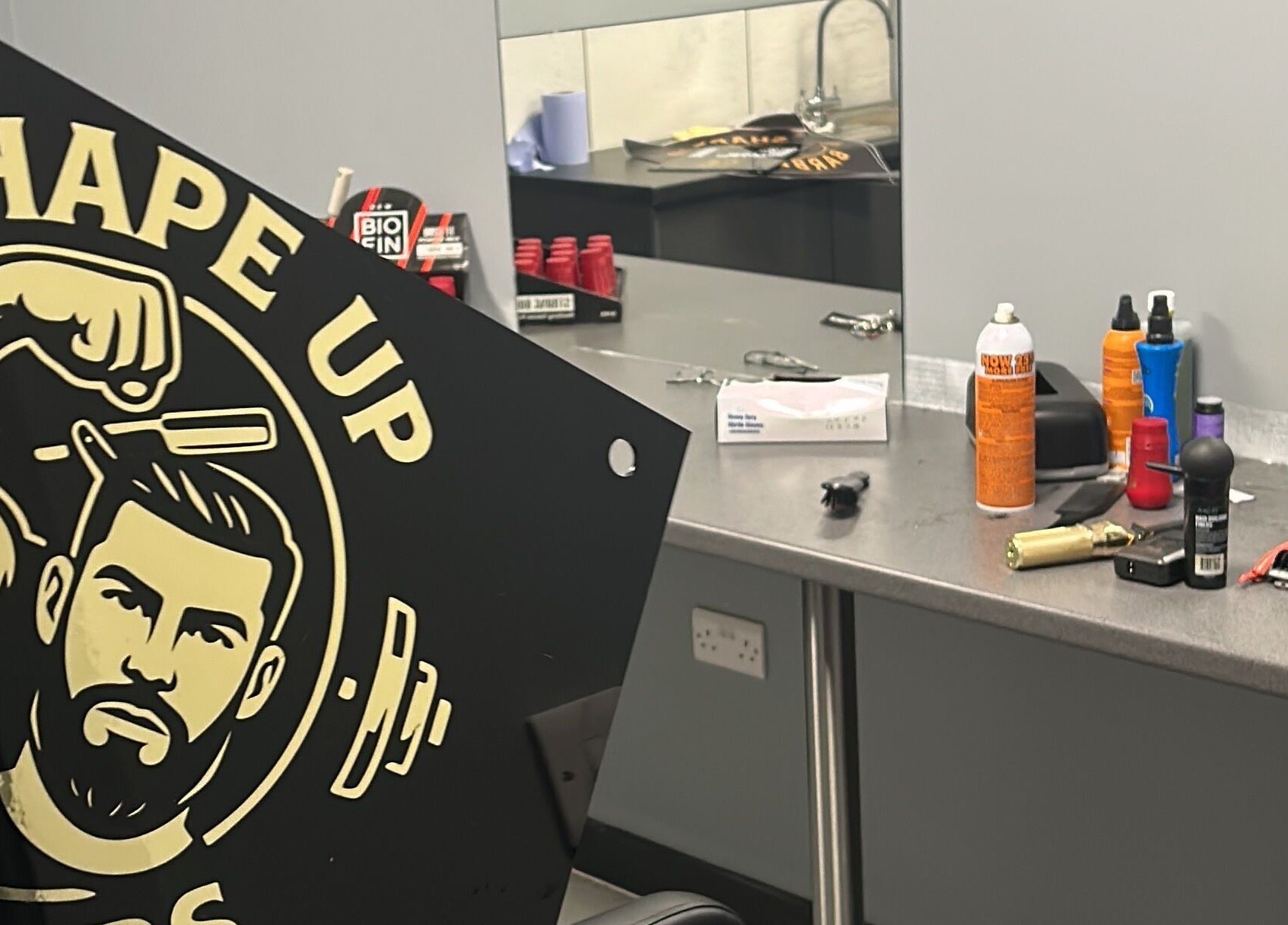 Interior of Shapeup.barbers in Bilston, England, displaying products and tools on a countertop.