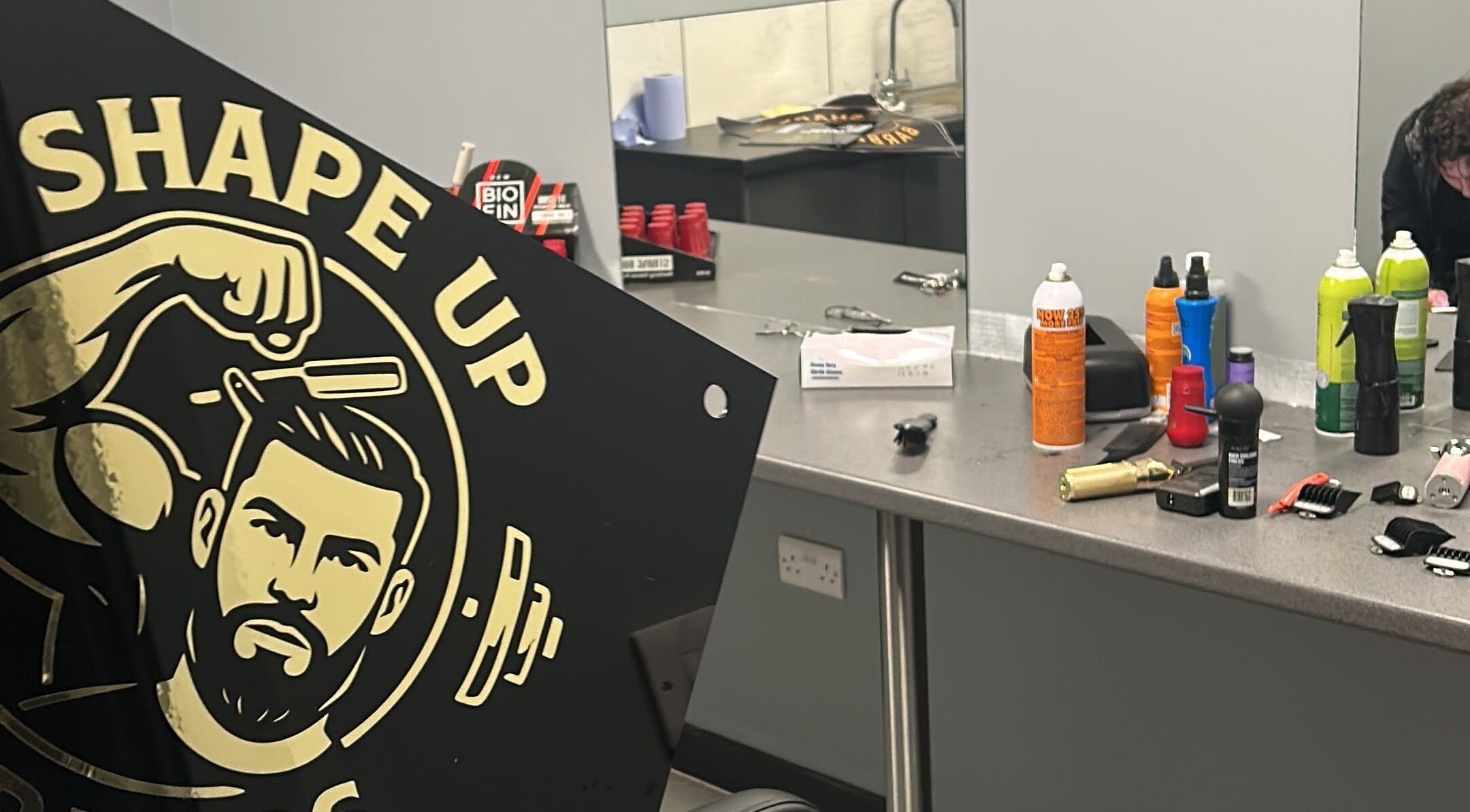 Interior of Shapeup.barbers in Bilston, England, displaying products and tools on a countertop.