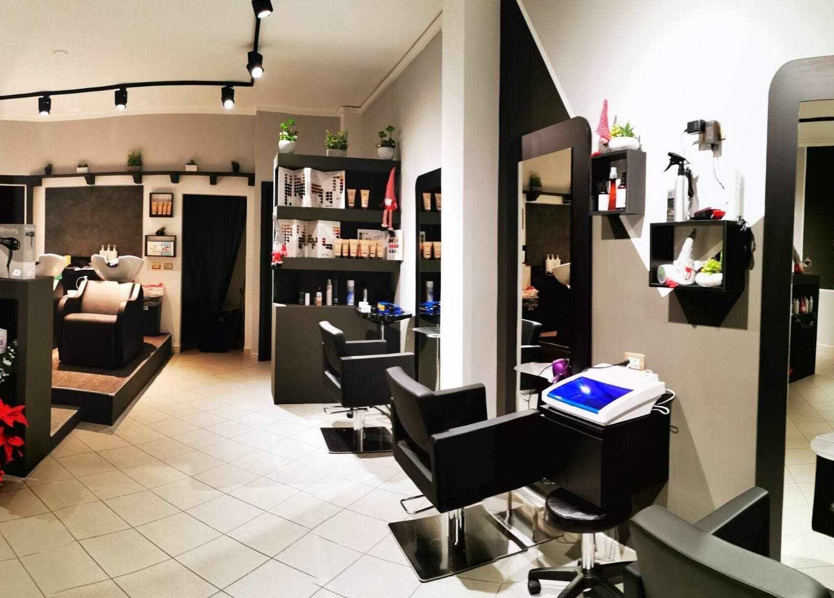 Interno di FD Hair Studio, Quartucciu, Sardegna, IT con sedie nere e scaffali eleganti.
