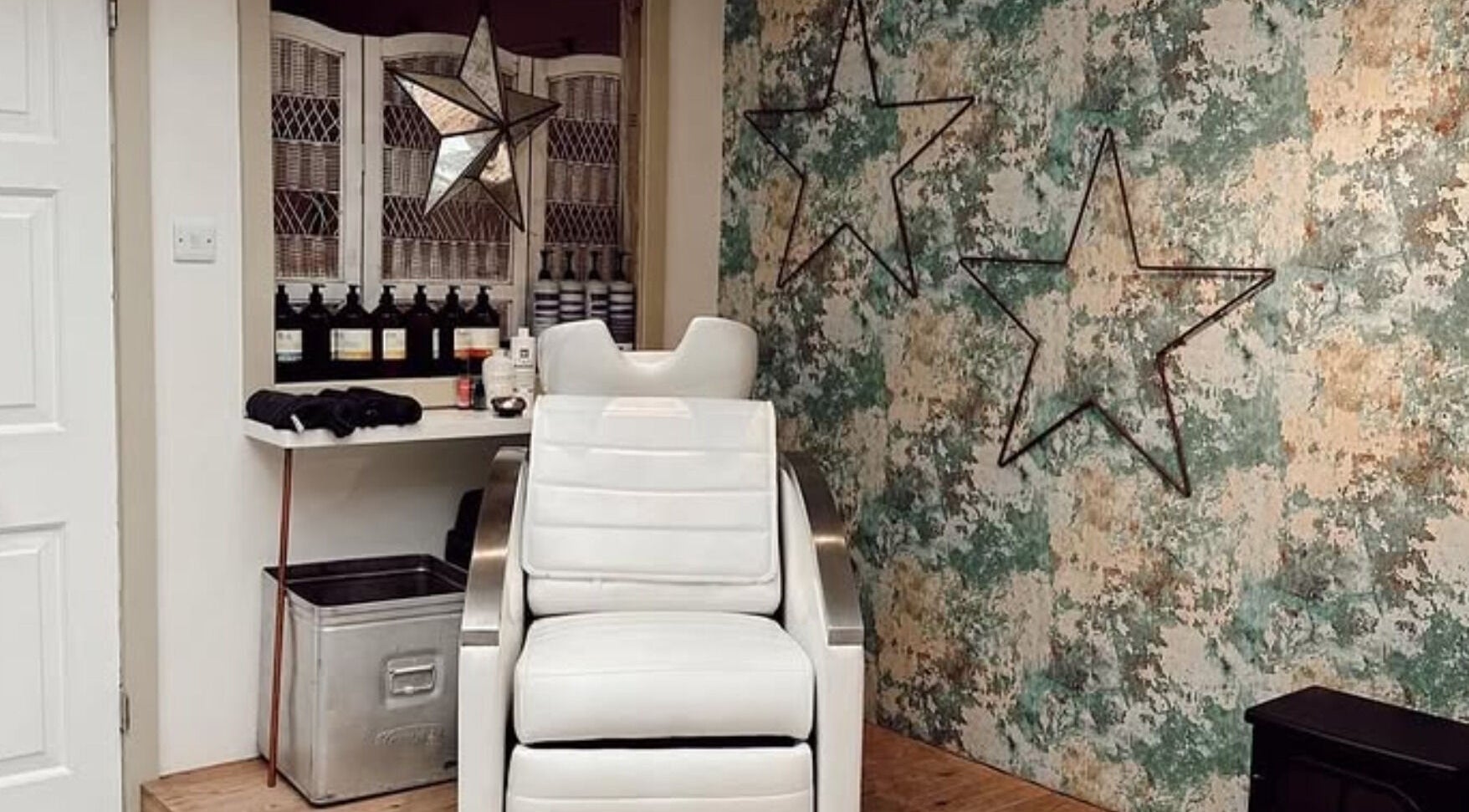 Chic styling chair at Phoenix Hair Studio, Wincanton, England, GB, with star decor and textured wall.