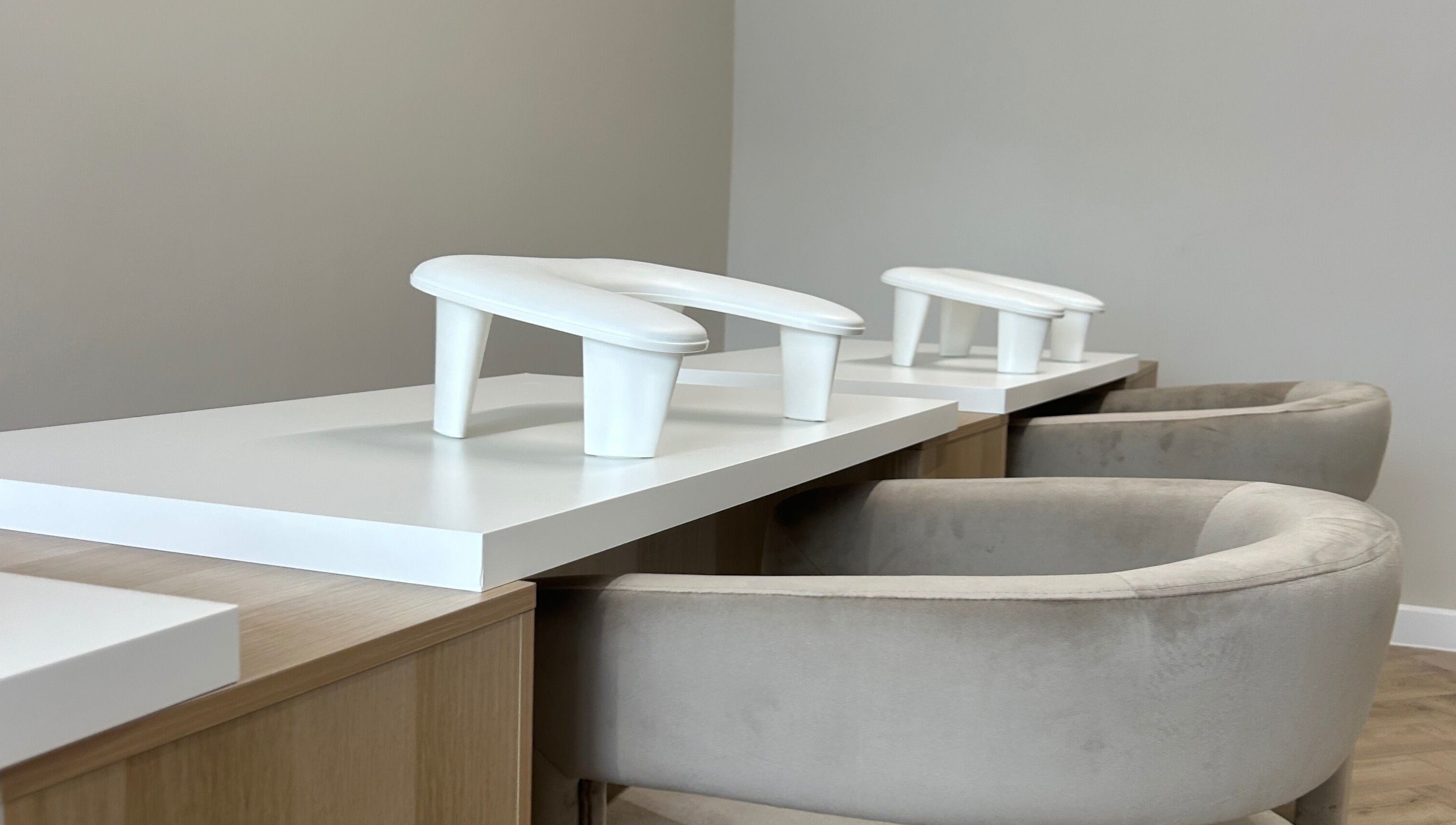 Modern manicure station at Pura Vida Salon, Plymouth, England, GB. Featuring sleek white accents and plush seating.