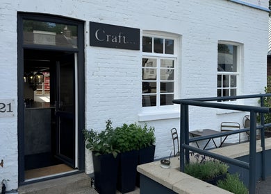 Entrance of Craft Hairdressing in Tring, England, GB with white brick exterior and inviting decor.