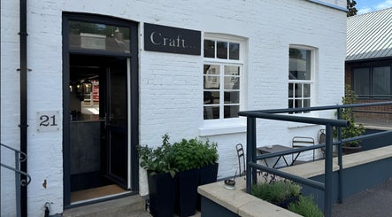 Entrance of Craft Hairdressing in Tring, England, GB with white brick exterior and inviting decor.