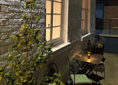 Ambient outdoor seating at Craft Hairdressing, Tring, England, GB, with a candle-lit table and lush plants.