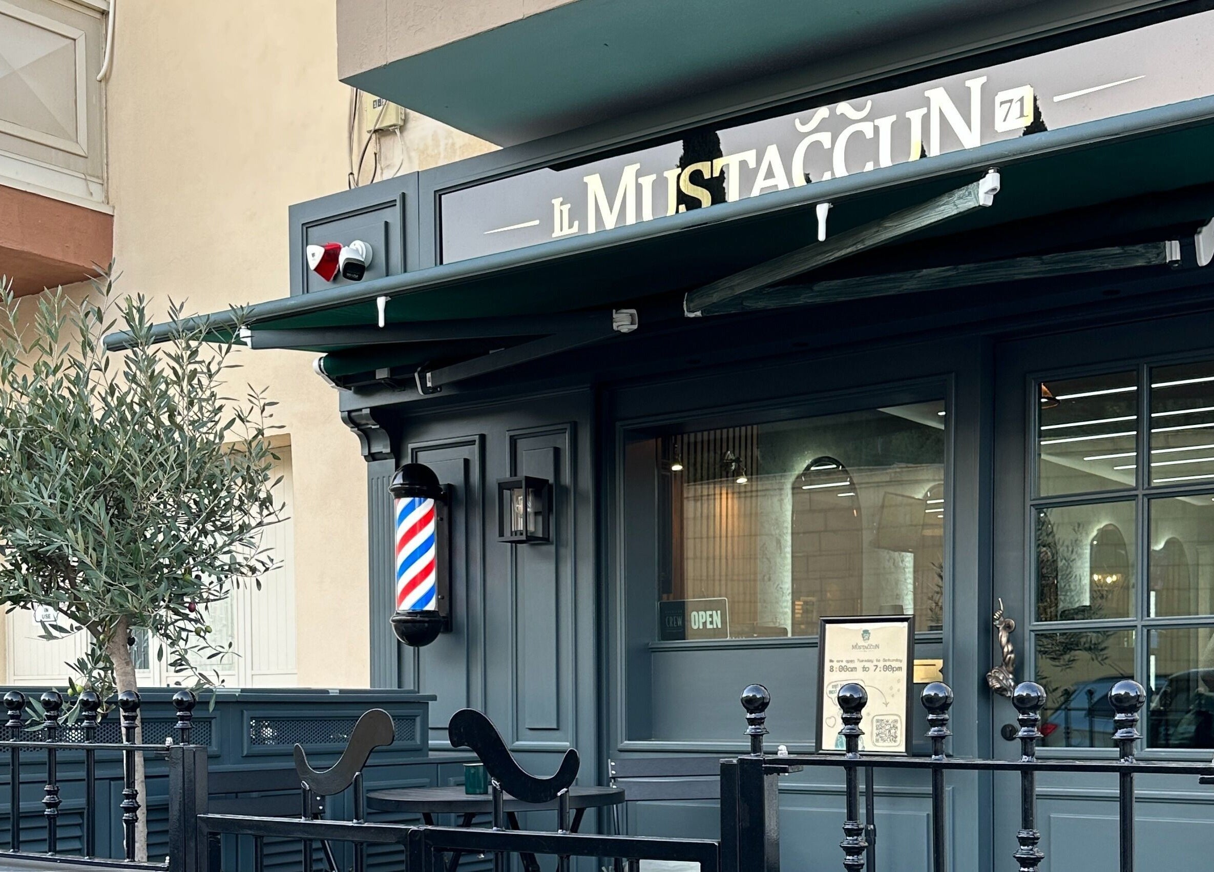 Exterior view of il-Mustaċċun Barber in Ħal Lija, MT with stylish black decor and barber pole.