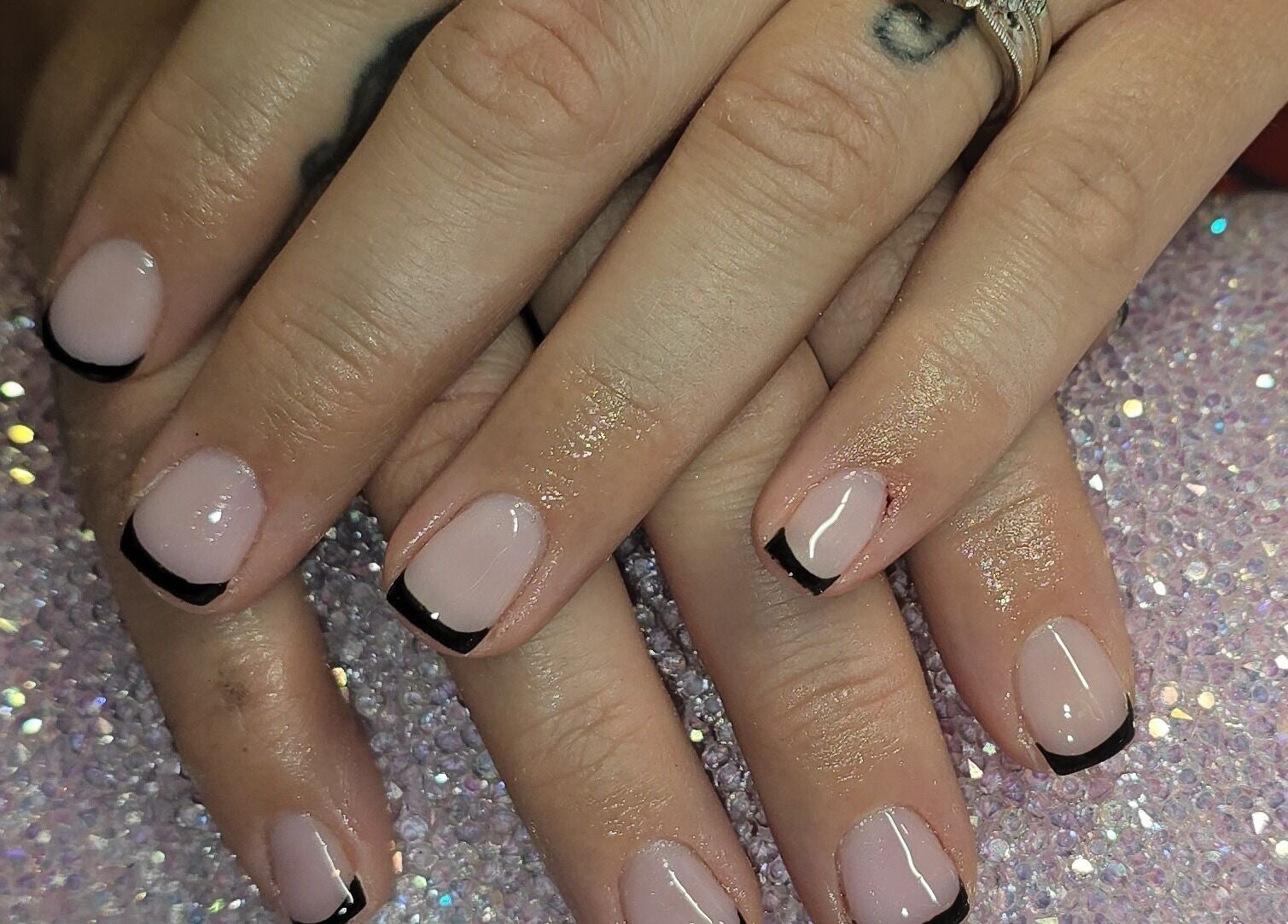 Elegant black French tips manicure at Nailed It By Laura, Carluke, Scotland, GB on sparkling surface.