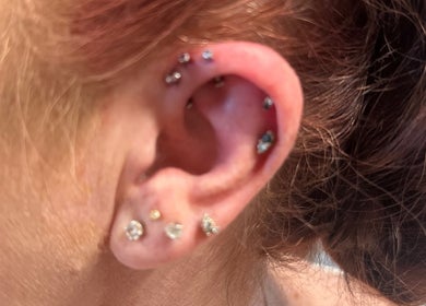Close-up of multiple ear piercings at Pierced in Tioga, North Dakota, US, showcasing sparkling jewelry.