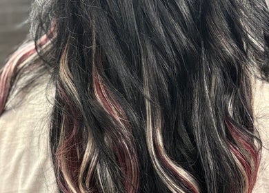 Close-up of highlighted black hair at Pierced, Tioga, North Dakota, US, showcasing trendy color technique.
