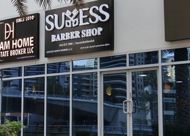 Front view of Success Barbershop in دبي, دبي, AE, showcasing large reflective windows and signage.
