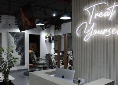 Modern interior of Success Barbershop in دبي, دبي, AE with stylish decor and 'Treat Yourself' neon sign.