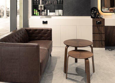 Stylish waiting area in Urban Global Barbershop, Abu Dhabi, with leather couch and wooden tables.