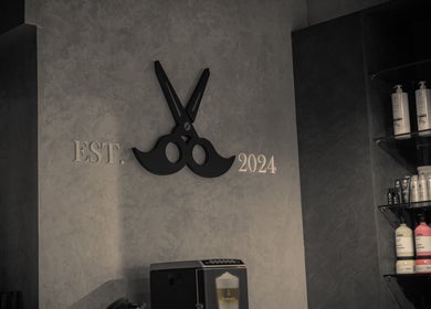 Interior of Urban Global Barbershop, Abu Dhabi, featuring scissors logo and product display.