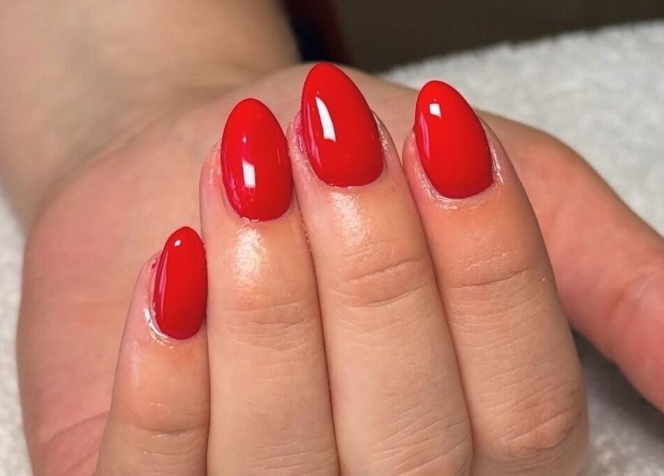 Bright red manicure at Rhea Manicure, Manchester, England, GB. Perfect glossy nail art showcasing expert craftsmanship.