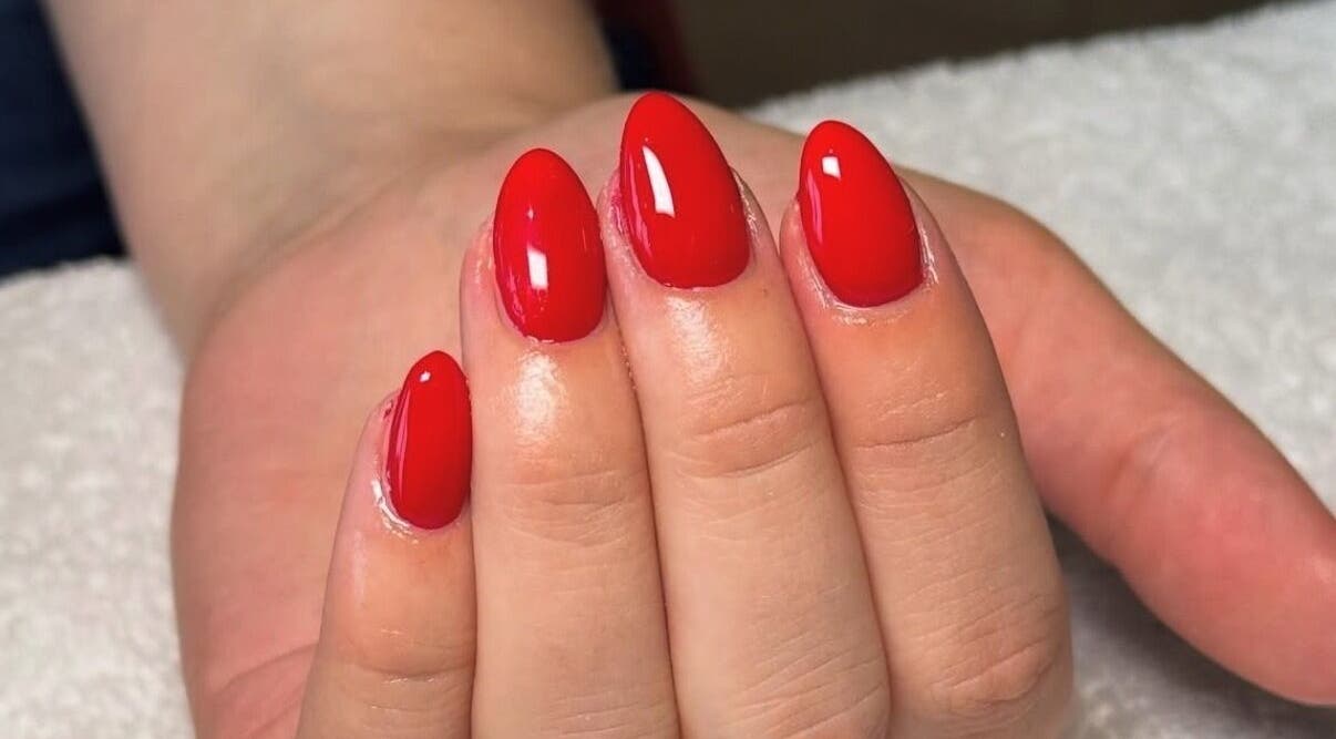 Bright red manicure at Rhea Manicure, Manchester, England, GB. Perfect glossy nail art showcasing expert craftsmanship.