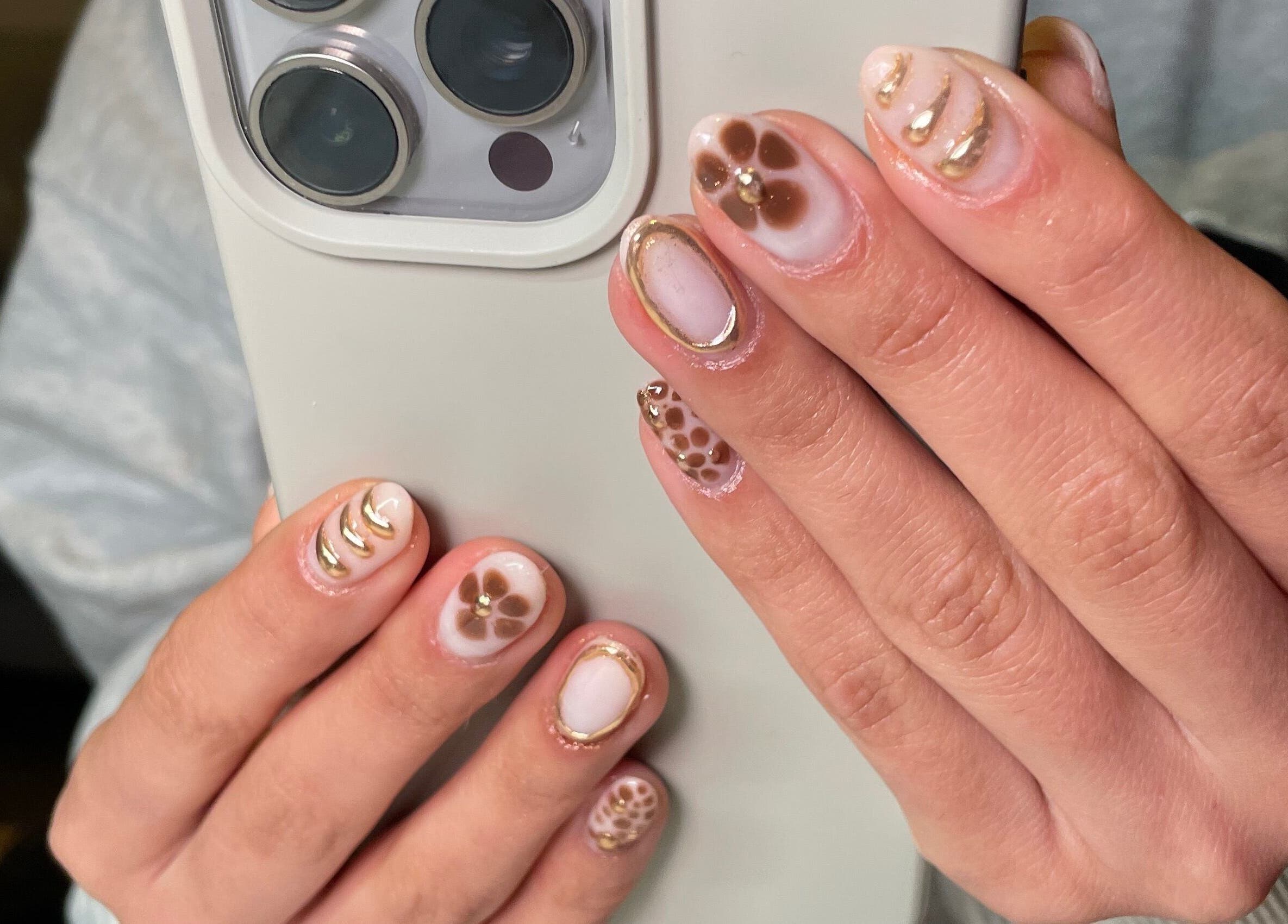 Close-up of artistic floral and gold nail art from Rhea Manicure, Manchester, England, GB.