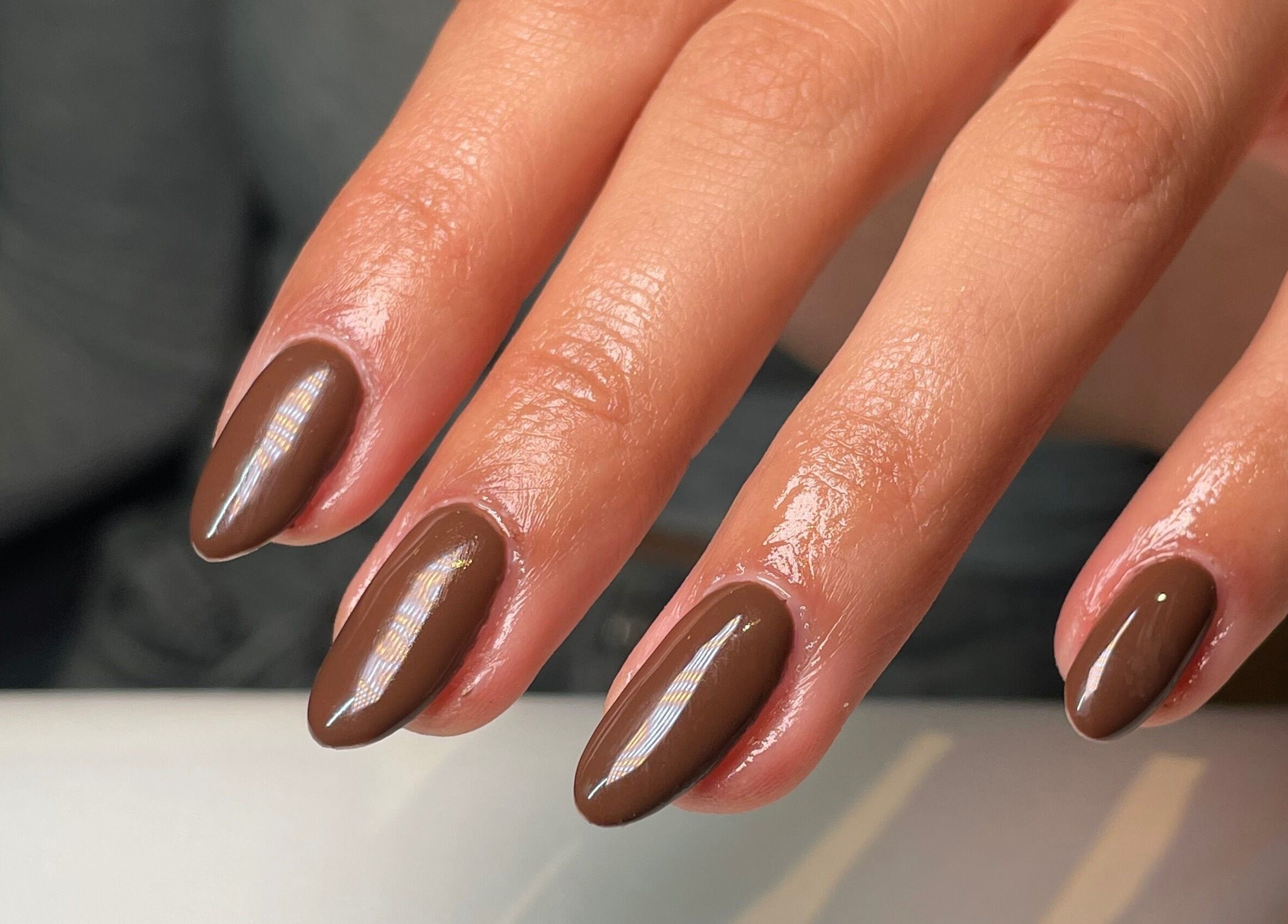 Elegant glossy brown manicure at Rhea Manicure, Manchester, England, GB, showcasing perfect nail care.