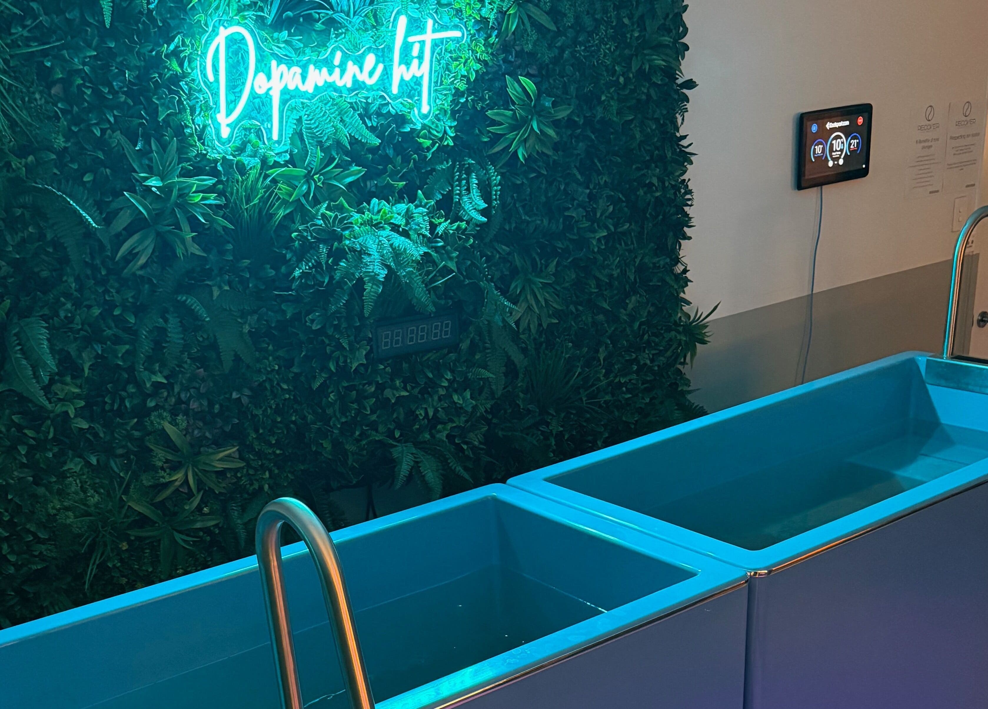 Tranquil spa setting at Recover and Refresh, Grafton, New South Wales, AU, with neon sign and serene water tubs.