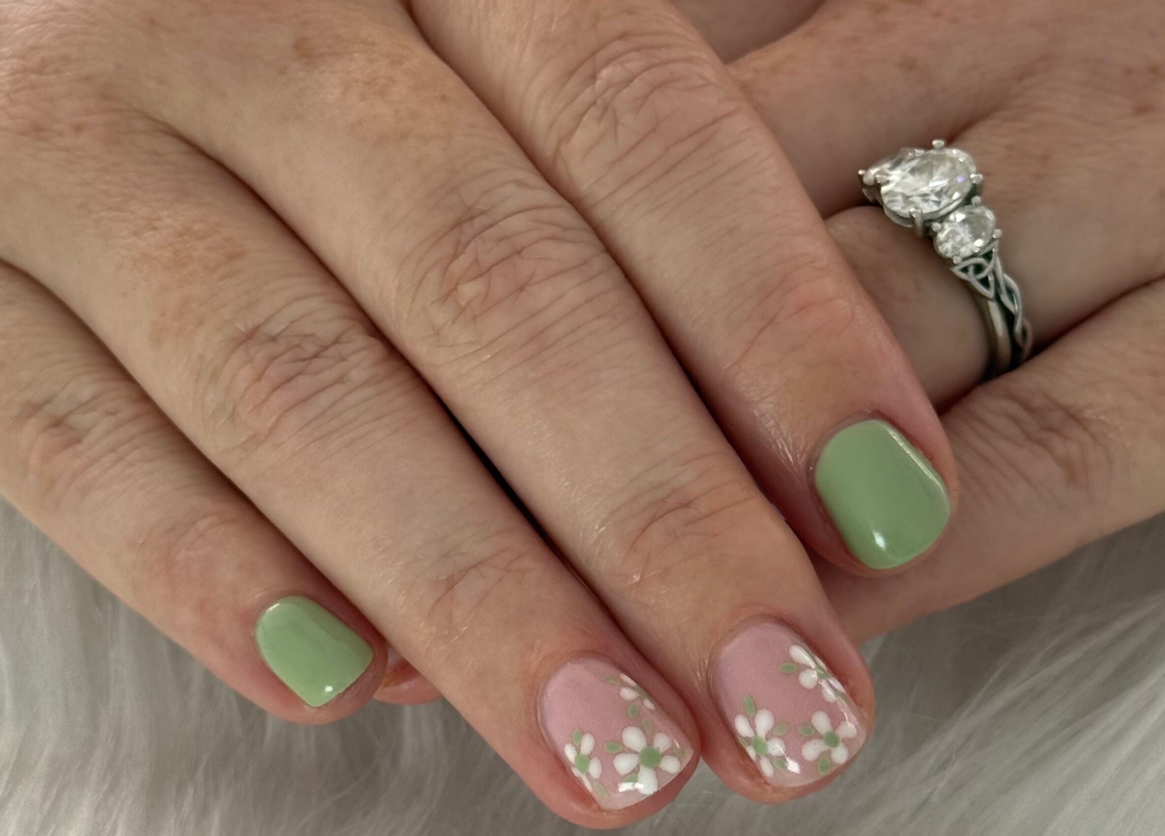 Fresh floral nail art at Creative Touch by RK in Tauranga, Bay of Plenty, NZ, showcasing green polish and ring.