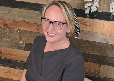Smiling professional at Beauty aesthetics by mel, St Helens, England, GB with a rustic wood background.