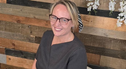 Smiling professional at Beauty aesthetics by mel, St Helens, England, GB with a rustic wood background.