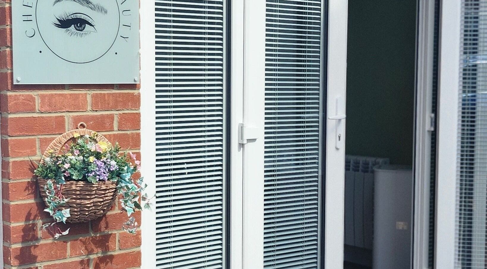 Entrance of Cherry Tree Beauty in Yaxley, England with a floral basket and brick wall.