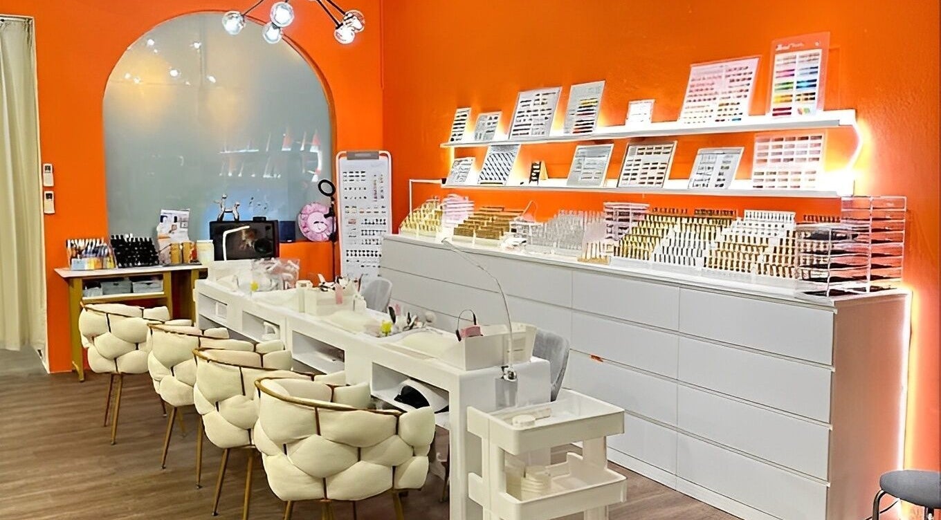 Stylish nail salon interior at Nails & Coffee, Singapore, Singapore, SG. Orange walls, modern chairs, manicure station.