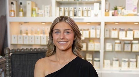 Smiling individual inside Mya Marie Esthetics, Holly, Michigan, surrounded by beauty products.