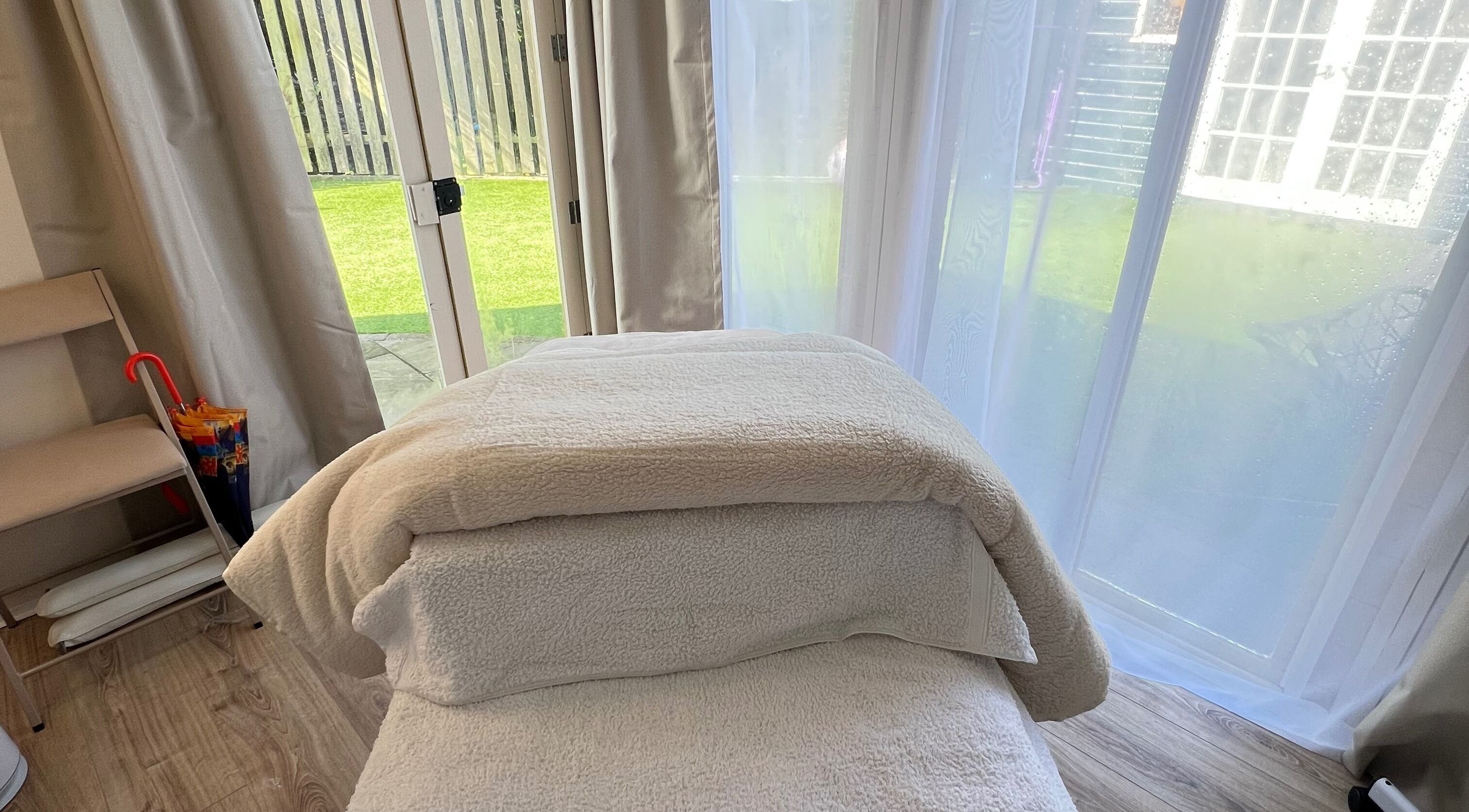 Relaxing treatment room at Serene Skin Solutions in Carluke, Scotland, GB with a massage table and garden view.