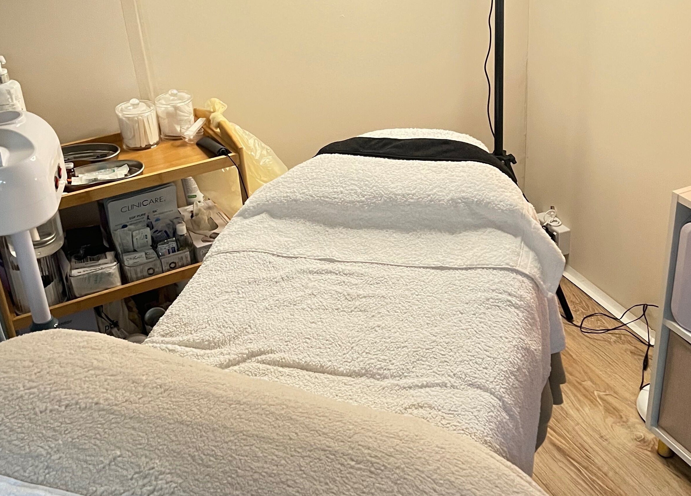 Cozy treatment room at Serene Skin Solutions, Carluke, Scotland, GB with a comfortable bed and skincare products.