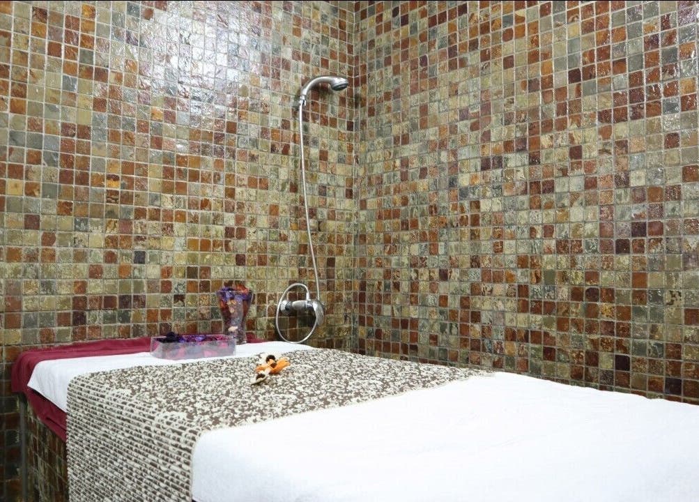 Massage room at Sumr Gents Saloon in Dubai, Dubai, AE with mosaic tiles and a prepared massage bed.