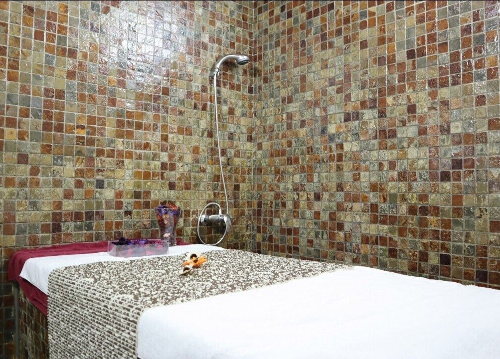 Massage room at Sumr Gents Saloon in Dubai, Dubai, AE with mosaic tiles and a prepared massage bed.