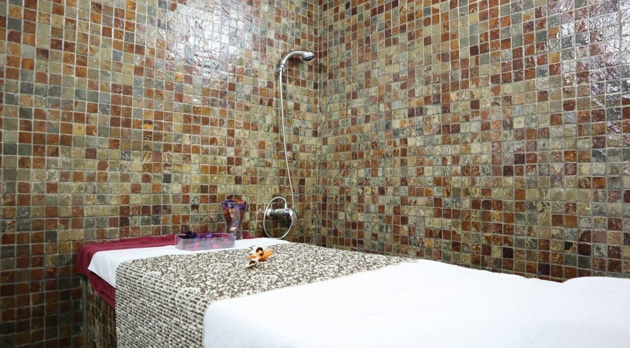 Massage room at Sumr Gents Saloon in Dubai, Dubai, AE with mosaic tiles and a prepared massage bed.