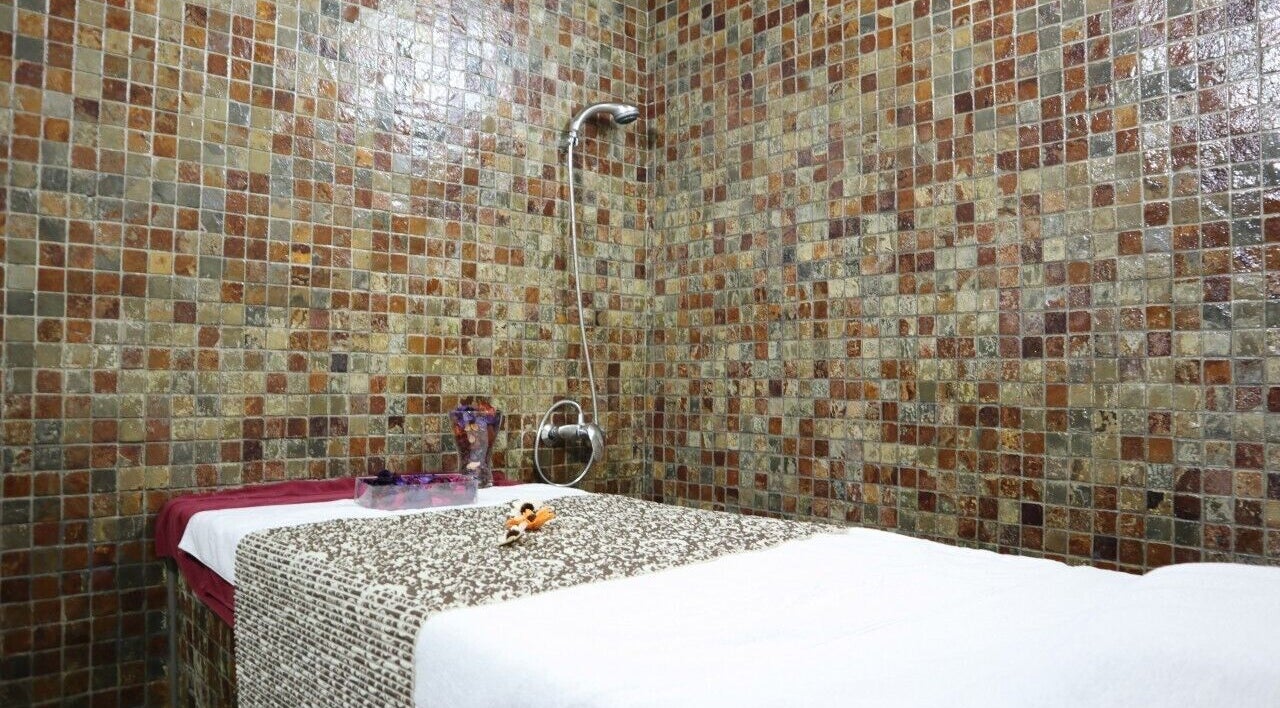 Massage room at Sumr Gents Saloon in Dubai, Dubai, AE with mosaic tiles and a prepared massage bed.