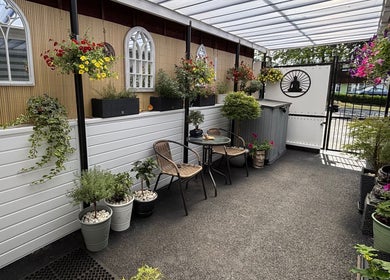 Charming garden patio at J.F Muscle Medic, Stourbridge, England, GB, featuring vibrant flowers and cozy seating.