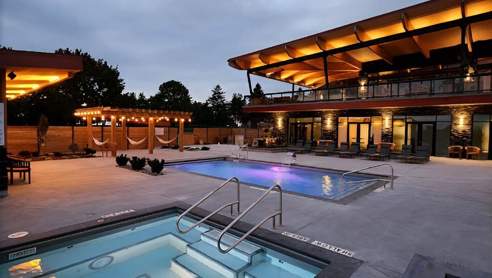 Illuminated pools and cozy hammocks at Wave Nordic Spa, Mount Elgin, Ontario, CA under twilight sky.